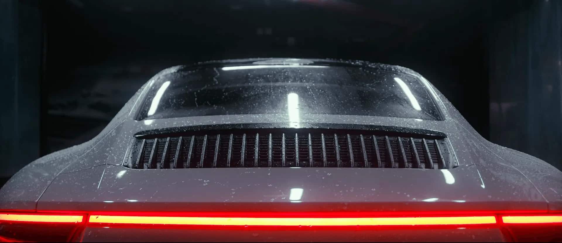 Rain-beaded hood and grille of a dark sports car detailed by Auto Gleam Details.